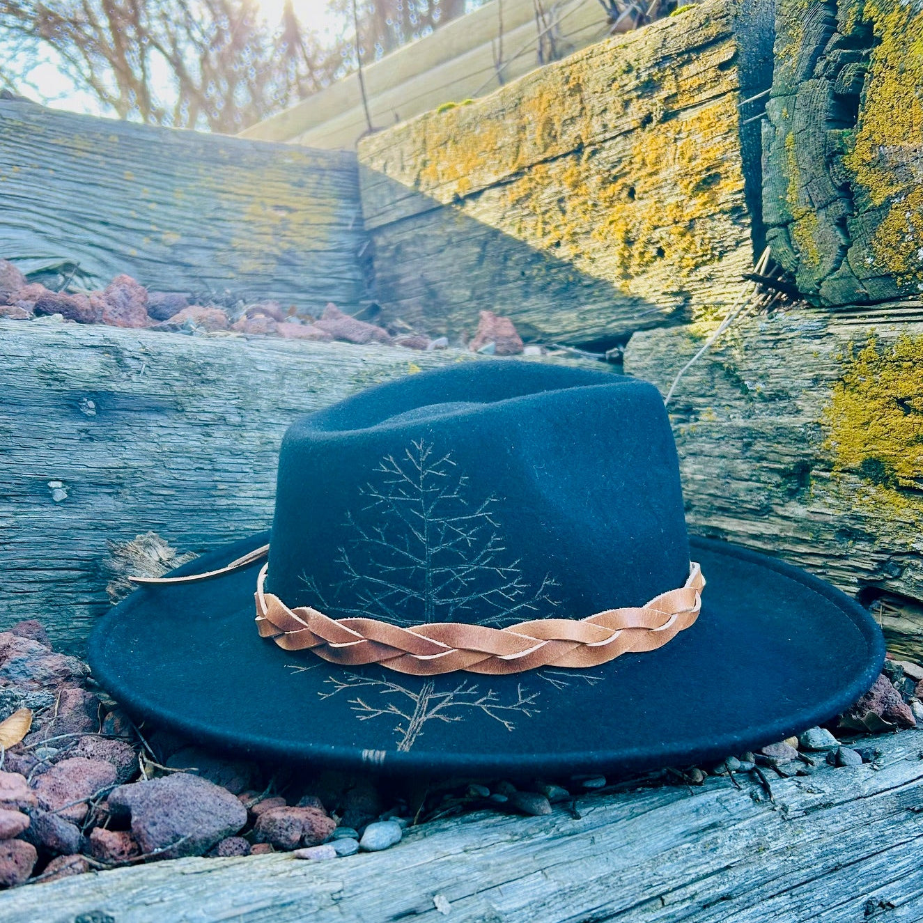 Black hat with custom burned artistry on the brim and crown accompanied by decorative, hand crafted band.
