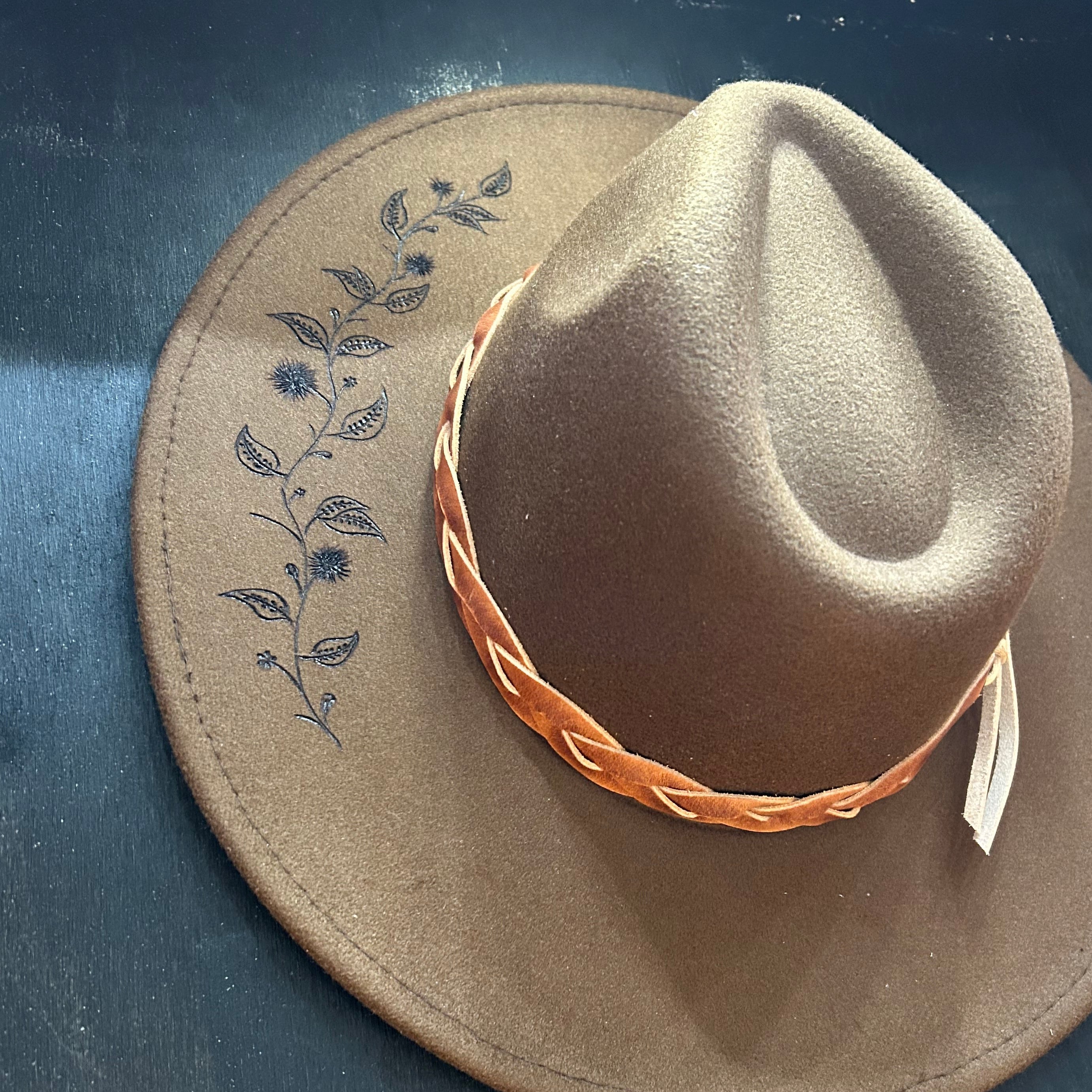 Organic, flowing vine design hand-burned into the felt of a custom wide-brim hat. Winding ivy and botanical silhouettes etched with a pyrography pen.