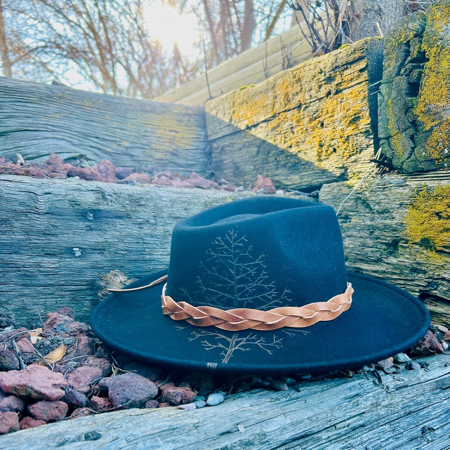 A hauntingly beautiful silhouette of a dormant forest etched into a wide-brim felt hat. Fine-line hand-burned tree branches and skeletal timber spanning from brim to crown.