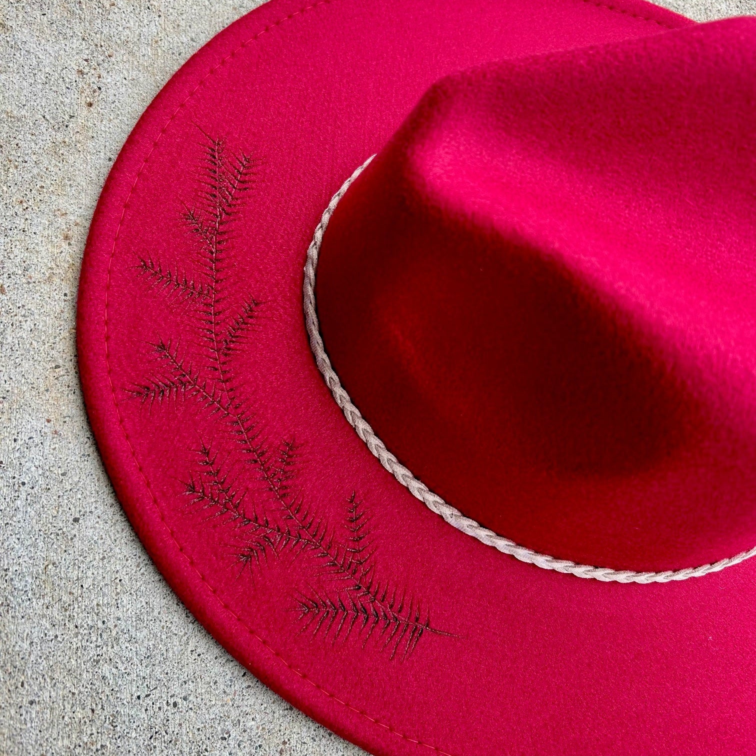 A quiet, minimalist design featuring a single hand-etched pine tree on a premium felt hat. A study in solitude and clean mountain style with a hand-burned evergreen silhouette.