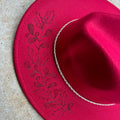 Hand-etched brim of sharp, resilient holly leaves and wild berries—a tribute to the flora that thrives when everything else fades. 